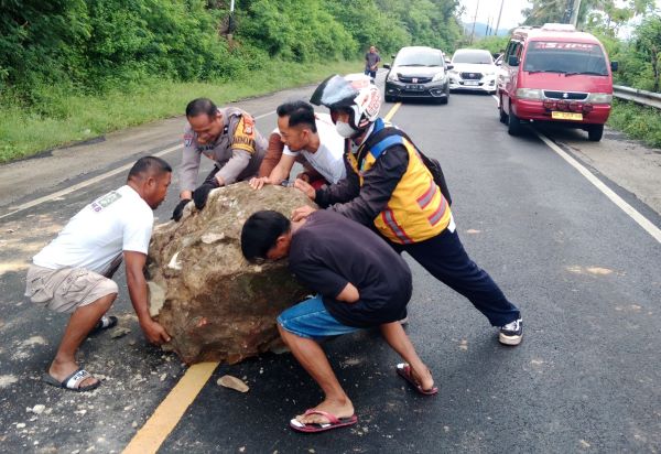 Bhabinkamtibmas Bersama Warga Bersihkan Bongkahan Batu di Jalan Trans Sulawesi